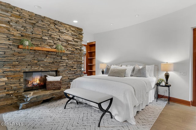 bedroom with light hardwood / wood-style floors and a fireplace