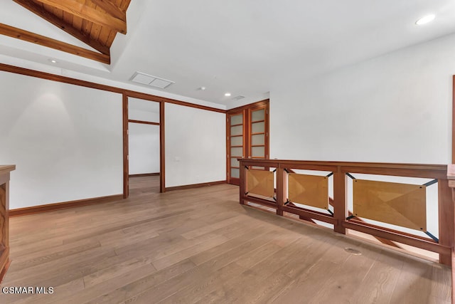 spare room with light hardwood / wood-style floors and vaulted ceiling with beams