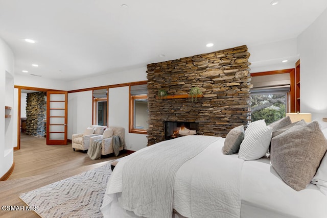 bedroom featuring light hardwood / wood-style floors, a closet, and a stone fireplace