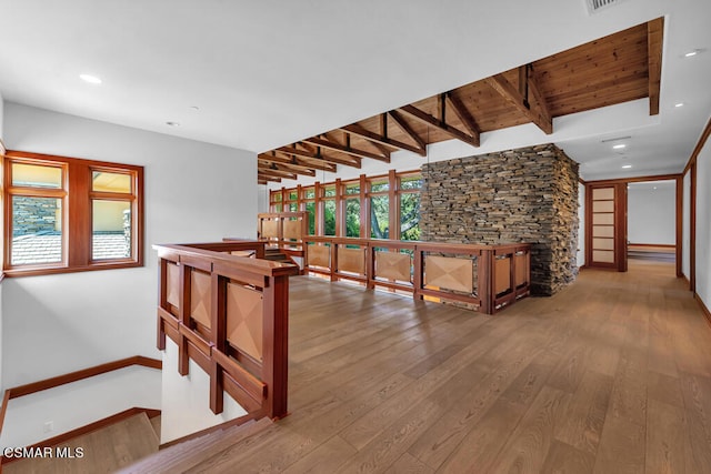 corridor featuring hardwood / wood-style flooring and vaulted ceiling with beams