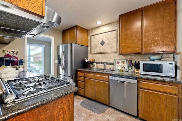 kitchen featuring range hood, sink, dark stone countertops, decorative backsplash, and stainless steel appliances