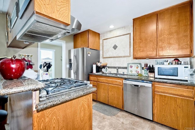 kitchen with sink, extractor fan, tasteful backsplash, dark stone countertops, and stainless steel appliances