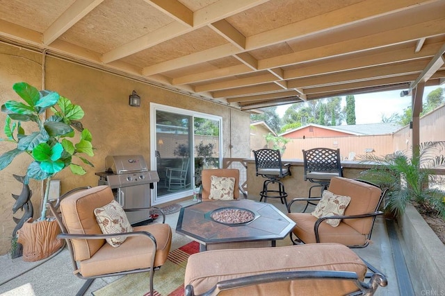 view of patio with area for grilling, an outdoor bar, and a fire pit