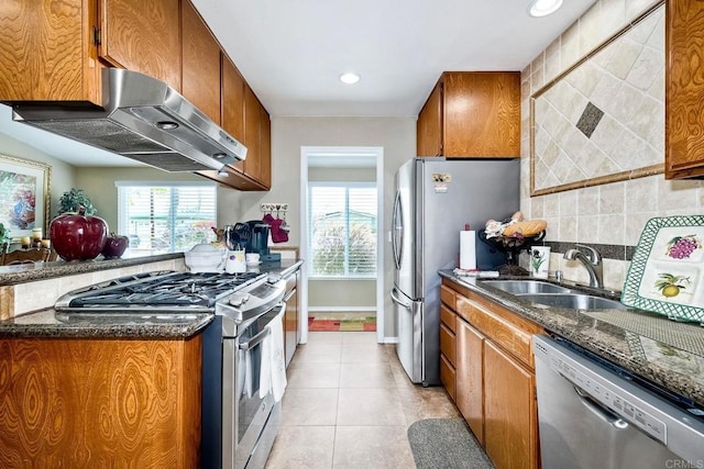 kitchen featuring light tile patterned flooring, sink, backsplash, stainless steel appliances, and wall chimney range hood