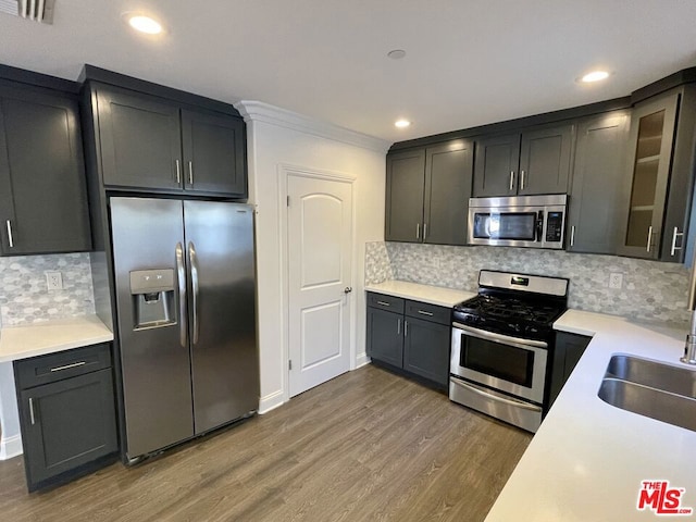 kitchen featuring appliances with stainless steel finishes, backsplash, ornamental molding, and dark hardwood / wood-style flooring