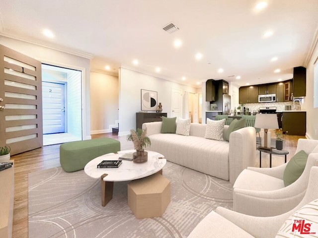 living room featuring crown molding and light hardwood / wood-style flooring