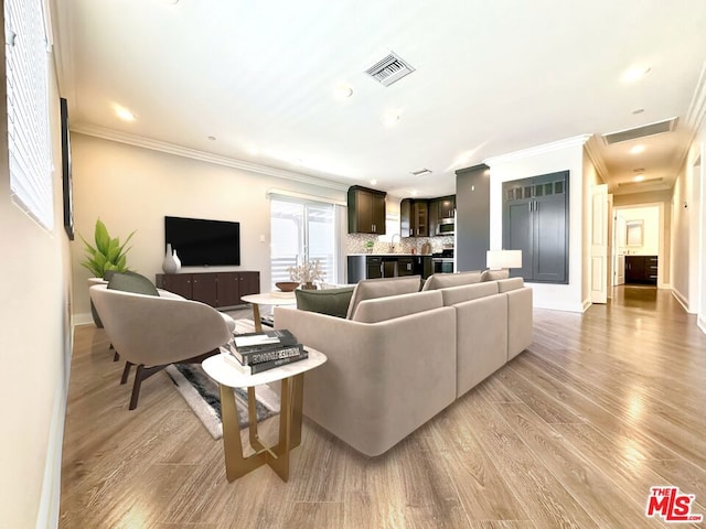 living room with crown molding, light hardwood / wood-style flooring, and sink