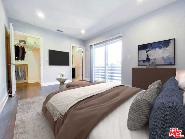 bedroom featuring a spacious closet, access to outside, and hardwood / wood-style flooring