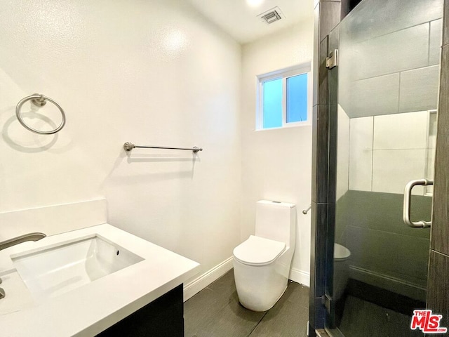 bathroom featuring tile patterned floors, vanity, a shower with door, and toilet