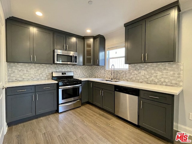 kitchen featuring gray cabinetry, tasteful backsplash, light hardwood / wood-style flooring, sink, and appliances with stainless steel finishes