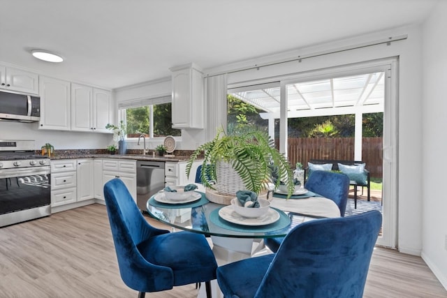 kitchen with light hardwood / wood-style flooring, white cabinets, appliances with stainless steel finishes, and sink