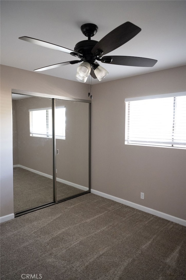 unfurnished bedroom with a closet, ceiling fan, multiple windows, and carpet floors