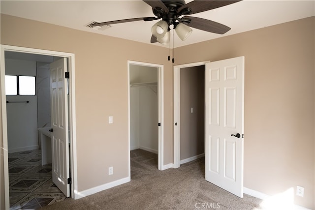 unfurnished bedroom with a closet, carpet, ceiling fan, and a walk in closet