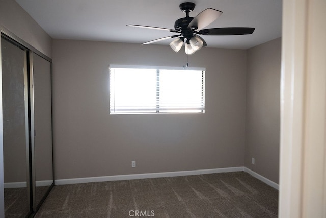 unfurnished bedroom featuring ceiling fan, a closet, and dark carpet