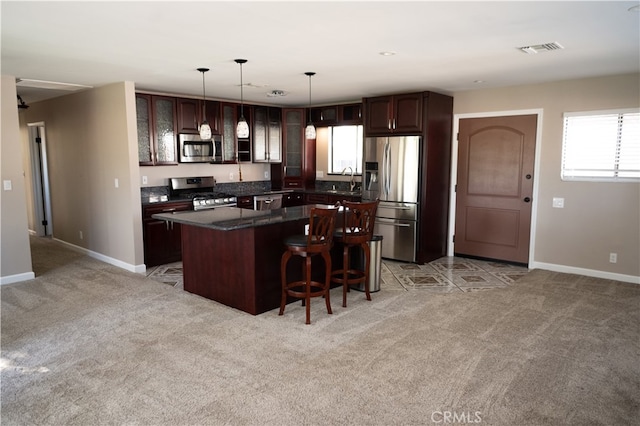 kitchen featuring a kitchen island, pendant lighting, stainless steel appliances, dark brown cabinets, and light carpet