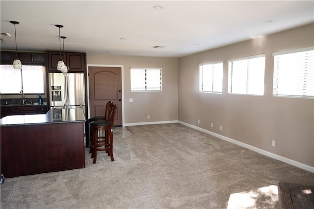 kitchen featuring stainless steel fridge, pendant lighting, dark brown cabinetry, sink, and light colored carpet