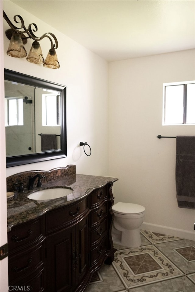 bathroom with a healthy amount of sunlight, tile patterned floors, vanity, and toilet