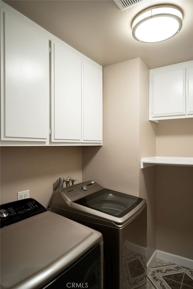 washroom featuring separate washer and dryer, tile patterned floors, and cabinets