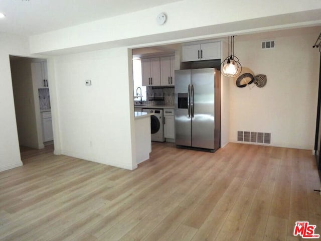 kitchen featuring stainless steel fridge with ice dispenser, backsplash, washer / dryer, and light wood-type flooring