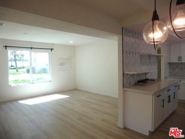 interior space with decorative light fixtures, light hardwood / wood-style floors, decorative backsplash, and white cabinets