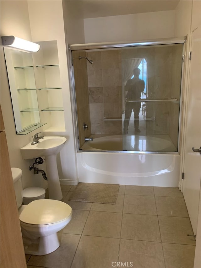 bathroom with tile patterned flooring, shower / bath combination with glass door, and toilet