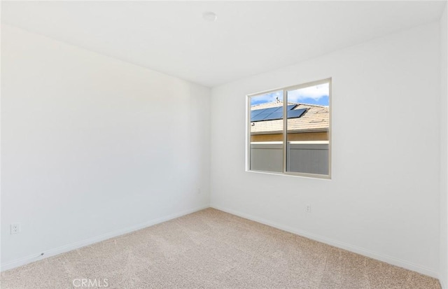 empty room featuring light carpet and baseboards