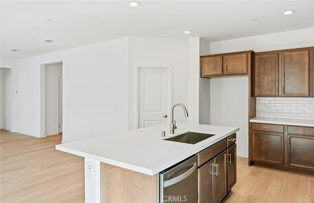 kitchen featuring light wood finished floors, decorative backsplash, a sink, light countertops, and stainless steel dishwasher