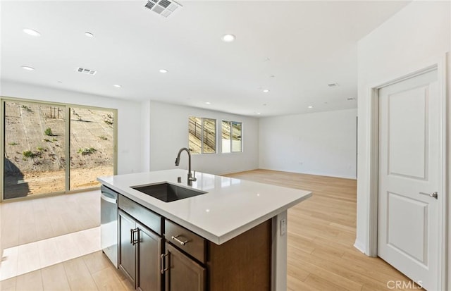 kitchen with light wood finished floors, stainless steel dishwasher, a sink, and visible vents