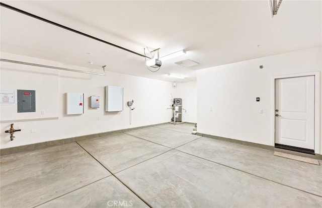 garage featuring a garage door opener, electric panel, and baseboards