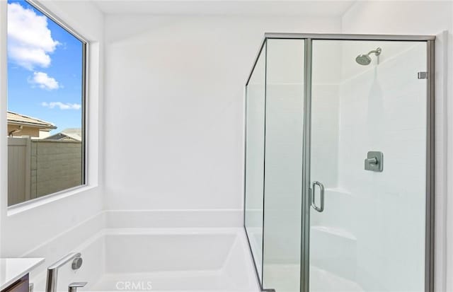 bathroom with a stall shower, vanity, and a bath