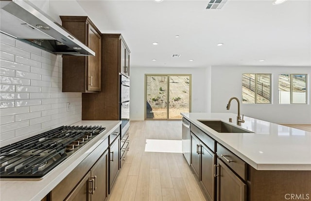 kitchen featuring a wealth of natural light, visible vents, appliances with stainless steel finishes, a sink, and wall chimney range hood