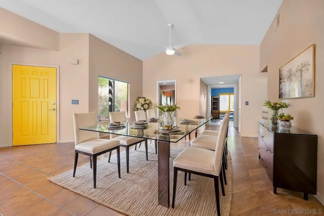 tiled dining room with ceiling fan and high vaulted ceiling