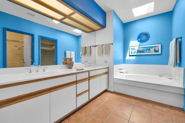 bathroom with vanity, a skylight, tile patterned floors, and plus walk in shower