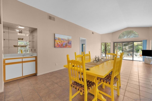 dining area with light tile patterned floors and vaulted ceiling