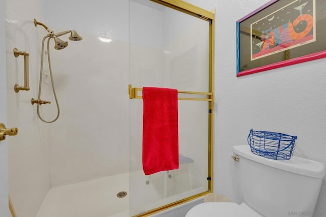 bathroom featuring toilet and a shower with door