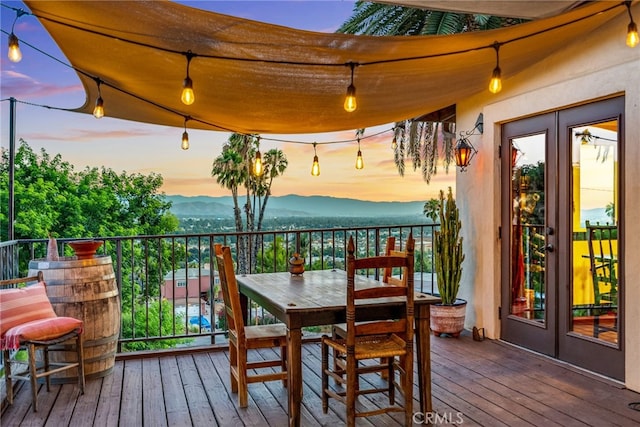 deck at dusk featuring a mountain view and french doors