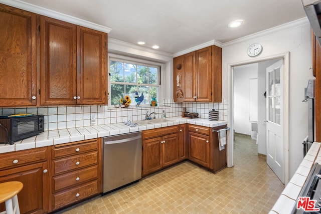 kitchen featuring backsplash, tile countertops, ornamental molding, and appliances with stainless steel finishes