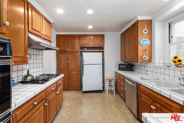 kitchen featuring tile countertops, decorative backsplash, black appliances, and ornamental molding