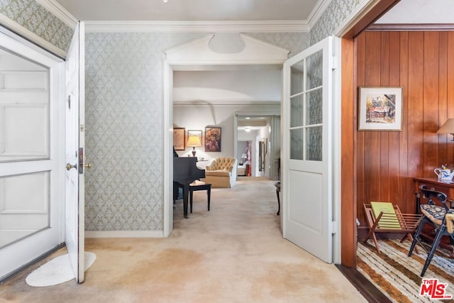 corridor with light carpet, ornamental molding, and wood walls