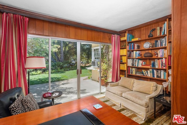 living area featuring ornamental molding, a healthy amount of sunlight, and wood walls