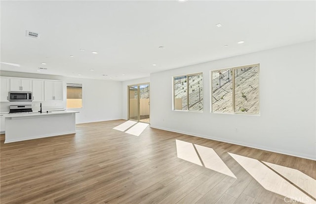 unfurnished living room with recessed lighting, visible vents, and light wood finished floors