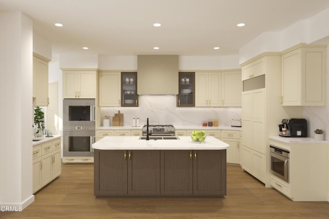 kitchen featuring wood-type flooring, sink, a center island with sink, extractor fan, and cream cabinets