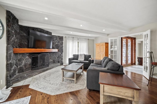 living room with hardwood / wood-style flooring, beam ceiling, french doors, and a stone fireplace