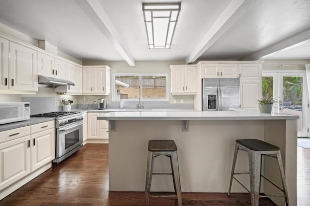 kitchen featuring stainless steel appliances, a kitchen breakfast bar, a kitchen island, beam ceiling, and white cabinets