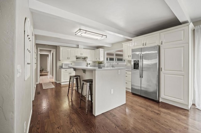 kitchen featuring white cabinetry, stainless steel fridge, a breakfast bar area, dark hardwood / wood-style floors, and a kitchen island