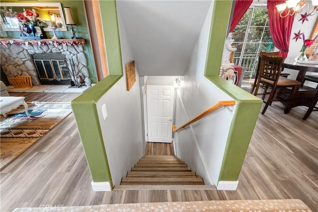 stairway with a fireplace and hardwood / wood-style floors