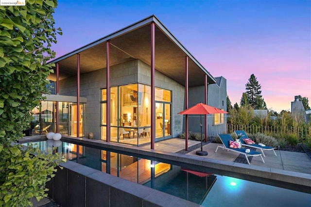 back house at dusk featuring a patio