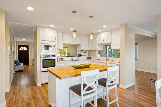 kitchen featuring white cabinets, light hardwood / wood-style flooring, and white appliances