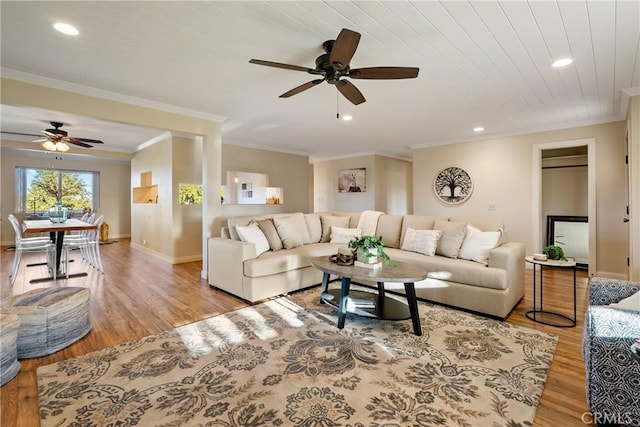 living area with crown molding, light wood finished floors, baseboards, and a ceiling fan
