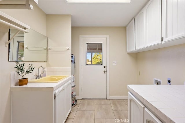 clothes washing area with light tile patterned floors, hookup for an electric dryer, a sink, baseboards, and cabinet space